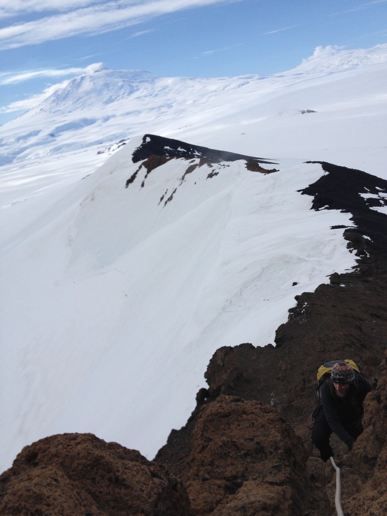 Richard hiking up Castle Rock. Behind is Mt. Erebus with some smoke blowing out the top.