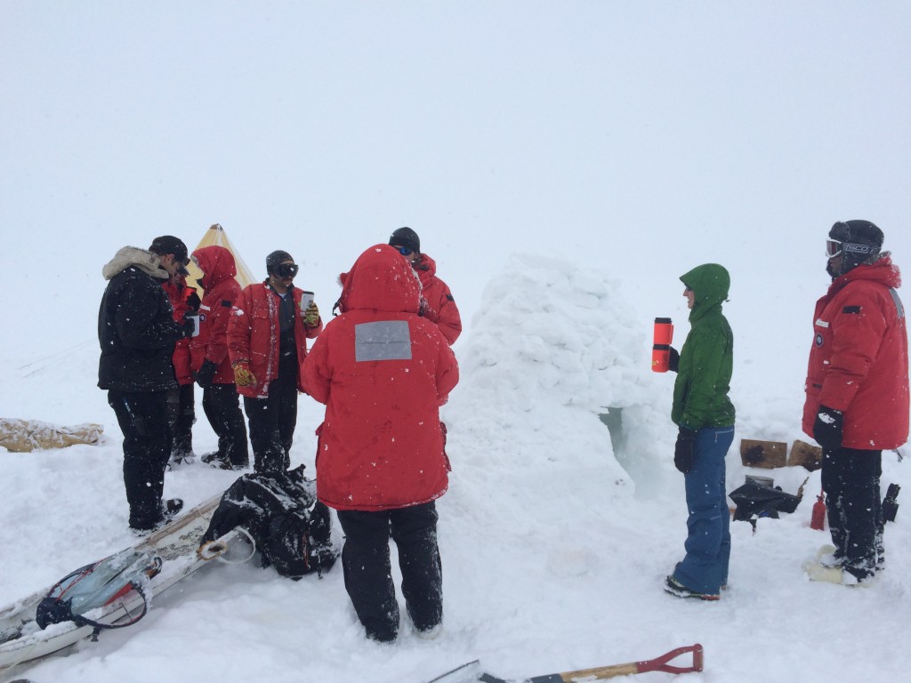 The whole group standing by the igloo drinking lukewarm cocoa. The stove had some trouble burning, so the water had some trouble heating. 